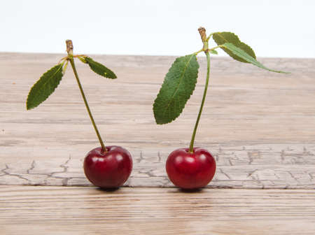 ripe cherry with leafs on wooden tableの写真素材