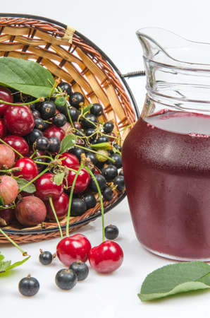 berries are scattered out of the basket and juice in a jug on a white backgroundの写真素材