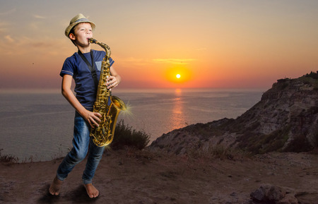 Teen playing saxophone in beach at sunsetの写真素材
