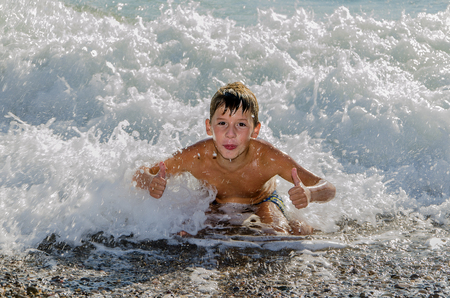 teenager swims on the sea pebbles in the surfの写真素材