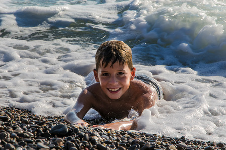 teenager lies on the sea pebbles in the surfの写真素材