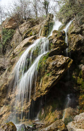 full-flowing waterfall in spring forestの写真素材