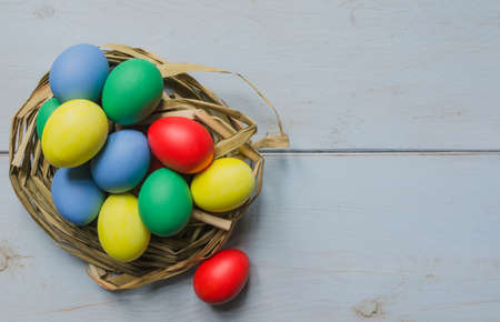 Easter eggs in straw nest on white wooden tableの写真素材