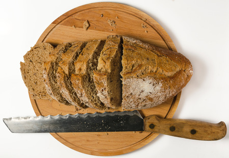 loaf of grain bread with knife on wooden cutting board