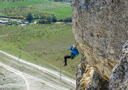young woman with a rope in sports of rock climbing on the rock