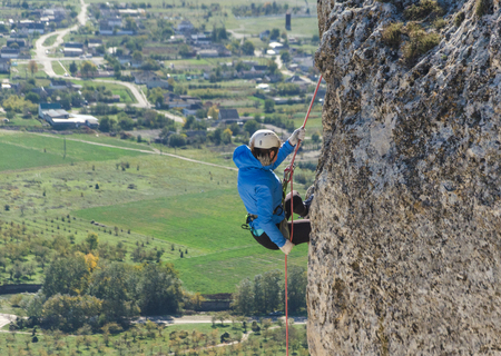 young woman with a rope in sports of rock climbing on the rockの写真素材