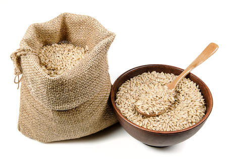pearl barley in bag and in ceramic bowl with wooden spoon on white backgroundの写真素材