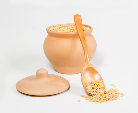 corn in ceramic pot and wooden spoon on white backgroundの写真素材