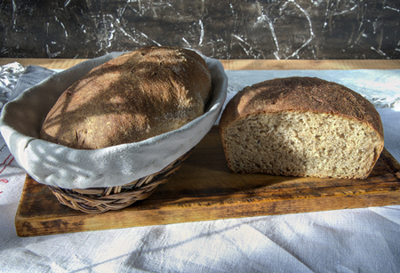 traditional homemade bread in the basket and cut loaf on cutting board