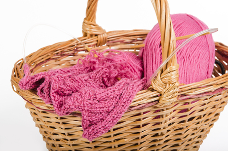 pink yarn in a wicker basket on a white backgroundの写真素材