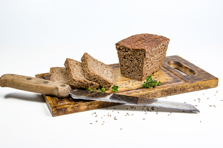 homemade bread with spices and knife on cutting board on white background