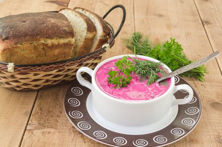 delicious beet soup in bowl with bread on old wooden tableの写真素材