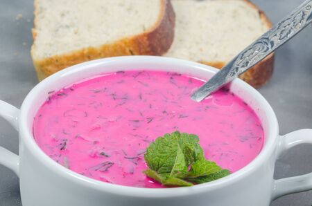 delicious beet soup in bowl with bread on dark