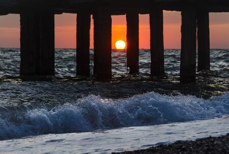 Silhouettes of berth at sunset and sea waves
