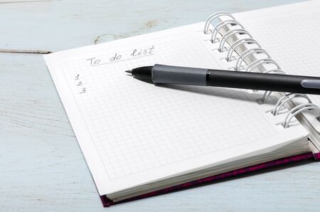 Open notebook on wooden table with pencil. The inscription in the notebook To do list