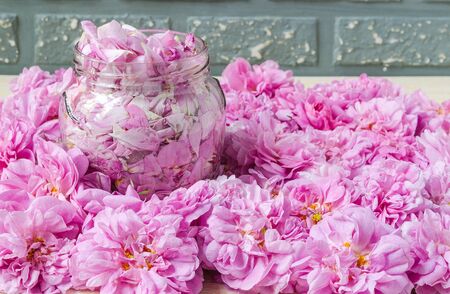 pink tea roses on table and petals in glass jarの写真素材