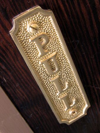 A close up of the Pull sing on a large wooden door