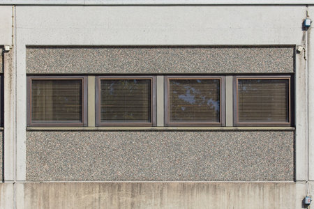 Windows with shades on a concrete wall.