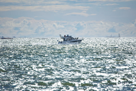 Motorboat silhouette on glistening sea in summer. Yachts on the horizon.