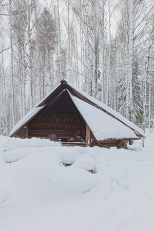 View of IdÃ¤npÃ¤Ã¤kallio wooden camping shelter and campfire site at Torronsuo National Park in cloudy winter weather, Tammela, Finland.の写真素材