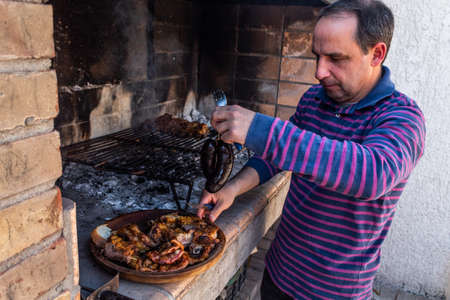 Skillful man cutting meat on wooden dish.の写真素材