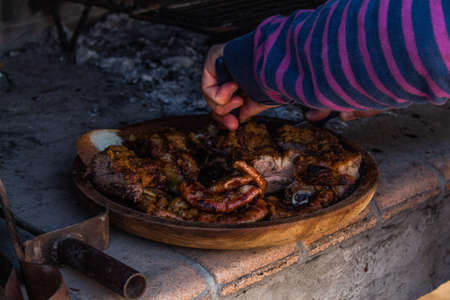 Skillful man hands cutting meat on wooden dish.の写真素材
