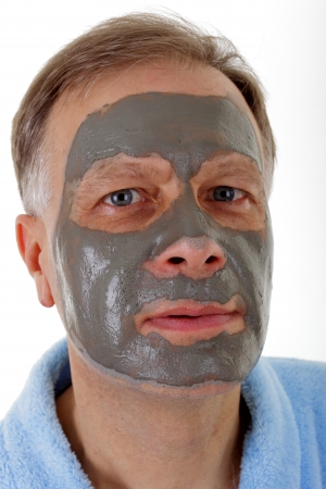 Man in a blue bathrobe with facial mask の写真素材