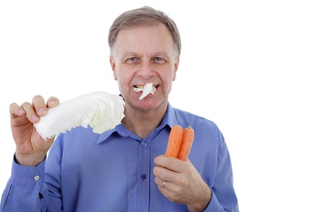 Handsome man eating loaf of chinese cabbage and holding two carrots の写真素材