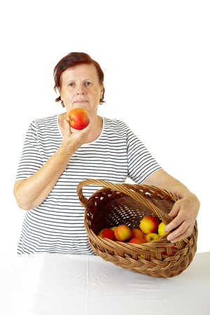  senior woman showing a wood basket full of red applesの写真素材