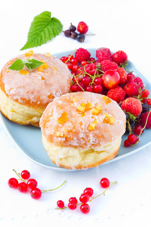 Two sugar glazed donuts with candied orange peel and fresh berries の写真素材