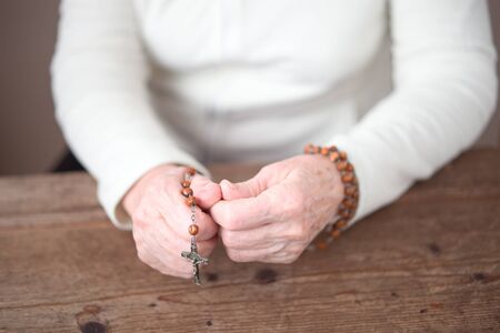 Elderly, female hands holding a wooden rosary with silver crossの写真素材