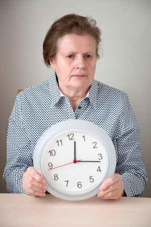 Senior woman holding a wall clockの写真素材