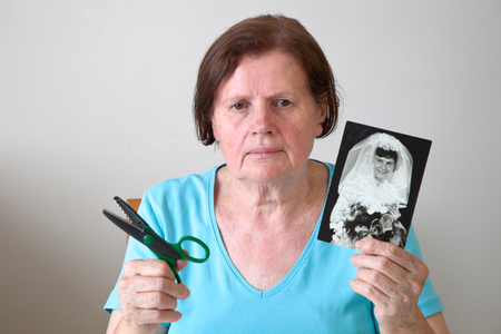 Mature woman cutting a wedding photo.の写真素材