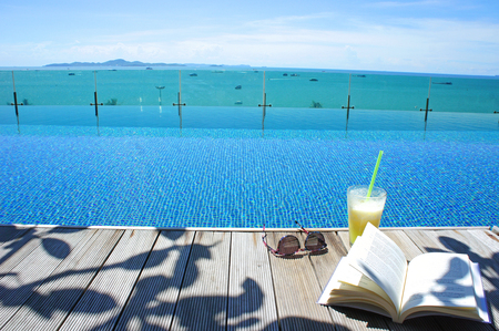 relax cocktail book sun glass at swimming pool with island viewの写真素材
