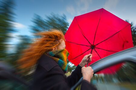 A woman tries to open her umbrella in a strong windの写真素材