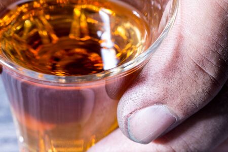 The dirty hand of a worker holding a glass of brandyの写真素材