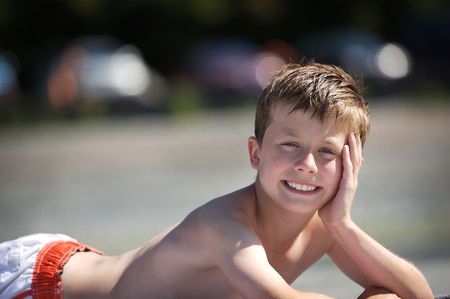 young boy laying on a beachの写真素材