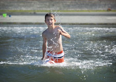 young boy running into the oceanの写真素材