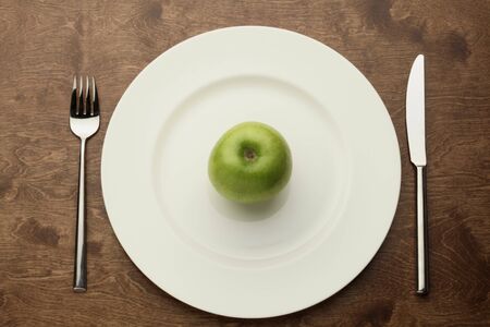 green apple on a white plate on a wooden tableの写真素材