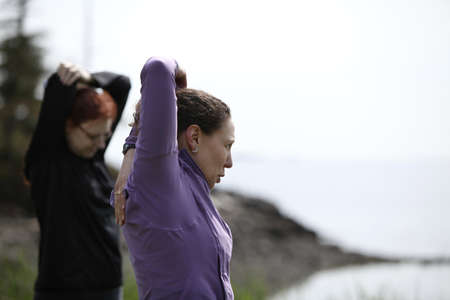 two women exercising and stretching in a parkの写真素材
