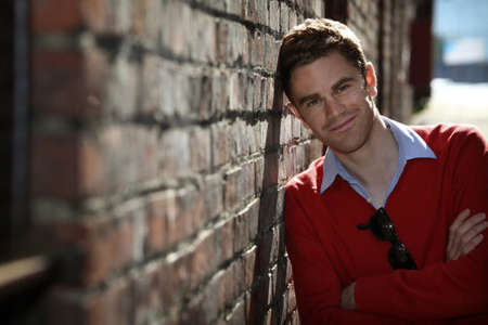 portrait of a young man leaning on a brick wallの写真素材