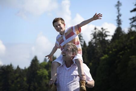 father with son on his shoulders at a beachの写真素材