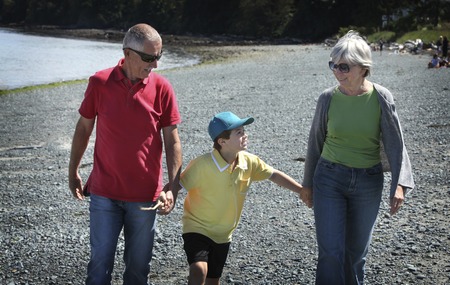 Grandparents with grandson walking at the beachの写真素材