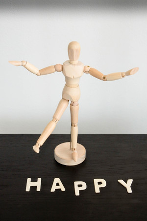 Happy, word arrangement with alphabet wood pieces and wood figure in happy action.の写真素材