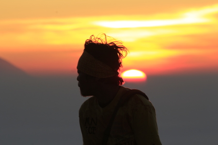 boy standing in front of sunriseの写真素材