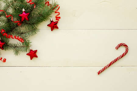 fir twigs with red balls in the form of stars on a white wooden background. New Year background, top...
