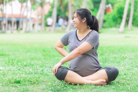 Pregnant woman work out in the green garden prepare her body for deliver a child.の写真素材