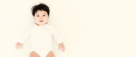 Adorable asian baby girl smiling on the bed with vintage tone. (Panoramic banner)の写真素材