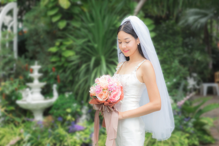 Beautiful woman holding flower with wedding suit in garden.の写真素材