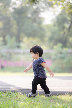 Adorable baby walking and learning outdoor park with vintage tone.の写真素材